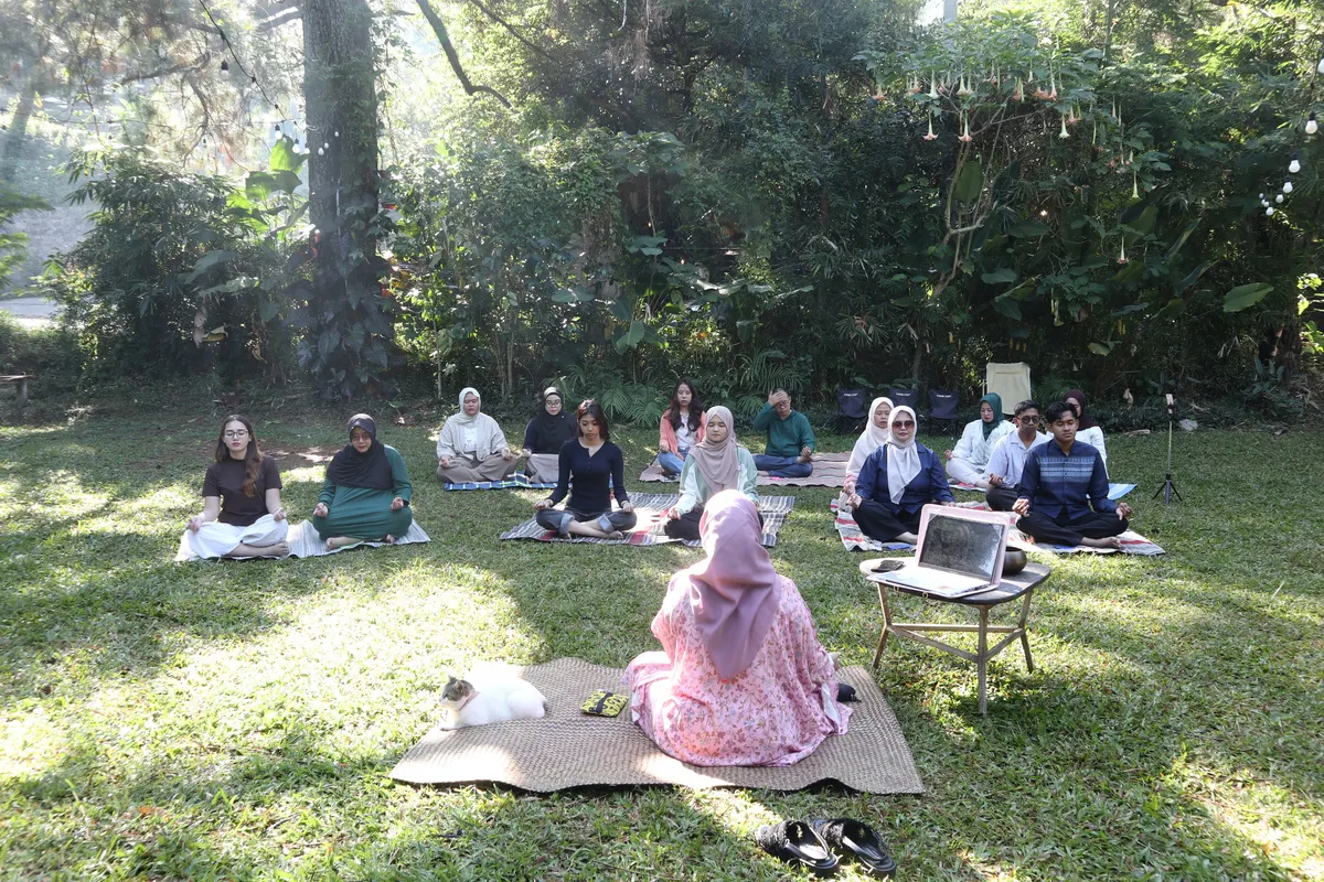 Peserta retreat bermeditasi di taman